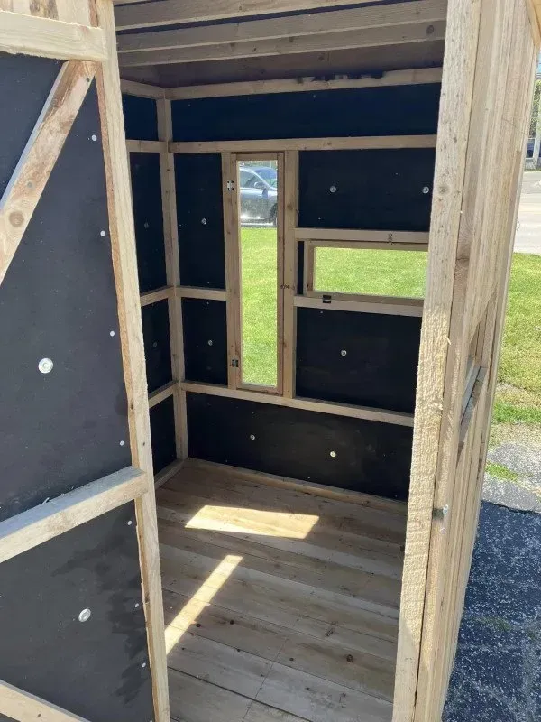 The inside of a wooden shed with black walls and a window.