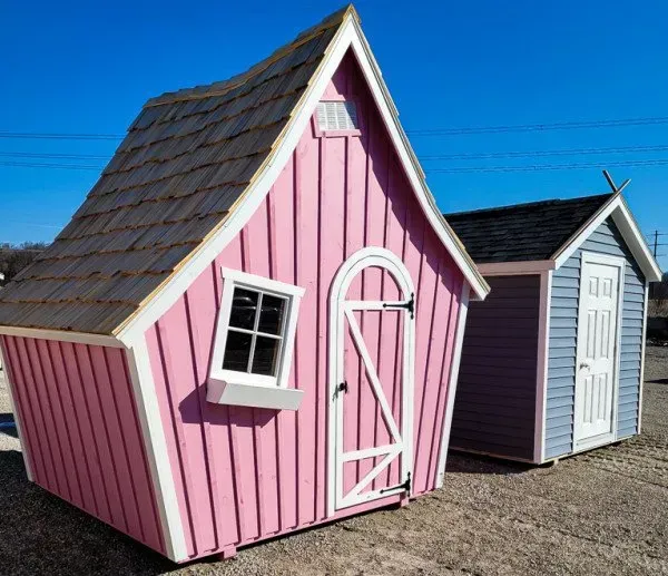 A pink and a gray shed are sitting next to each other