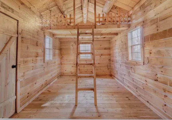 A wooden cabin with a ladder leading up to the second floor