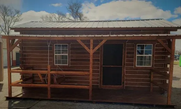 A small log cabin with a porch and a metal roof.