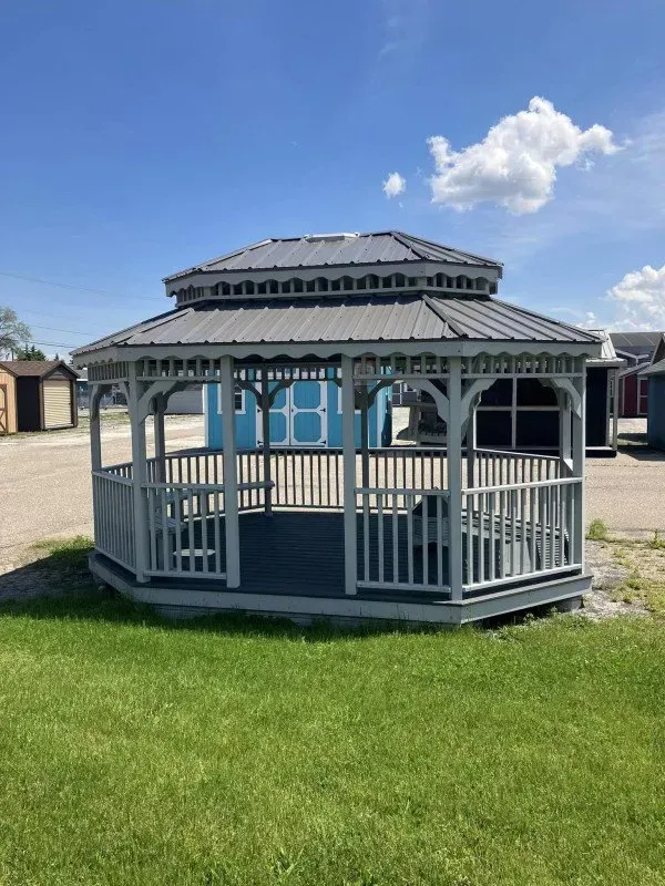 A gazebo is sitting in the middle of a lush green field.