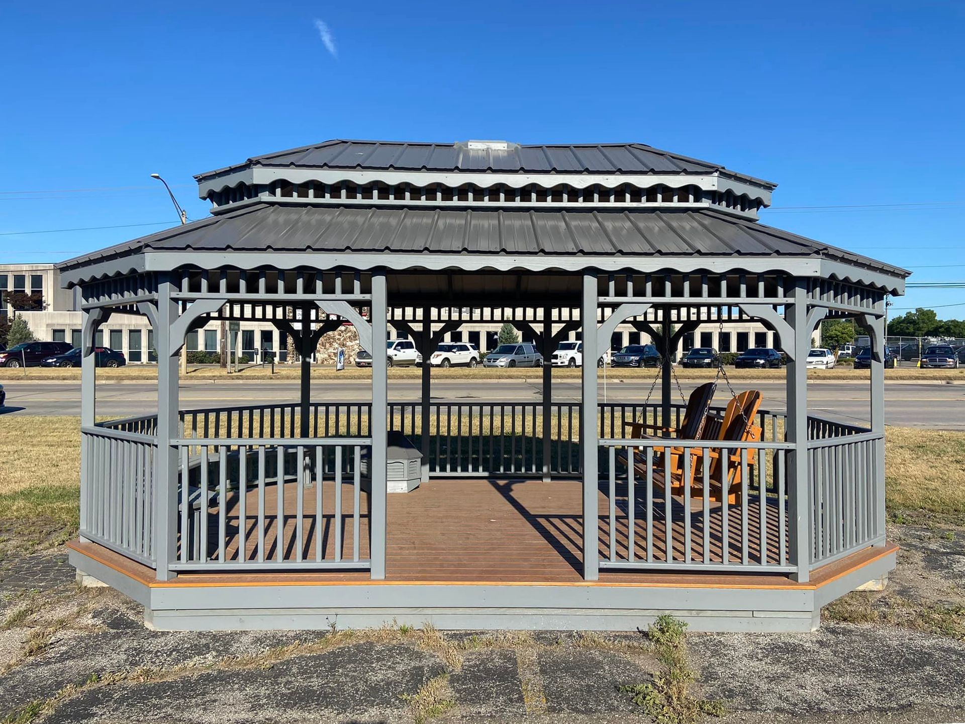 A gazebo with chairs underneath it is sitting in the middle of a field.