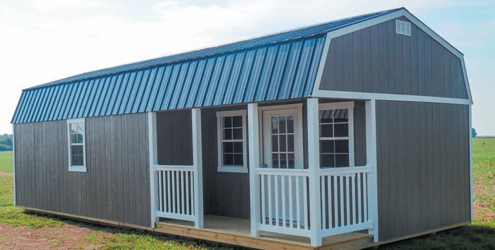 A shed with a porch and a blue roof is sitting in the middle of a field.