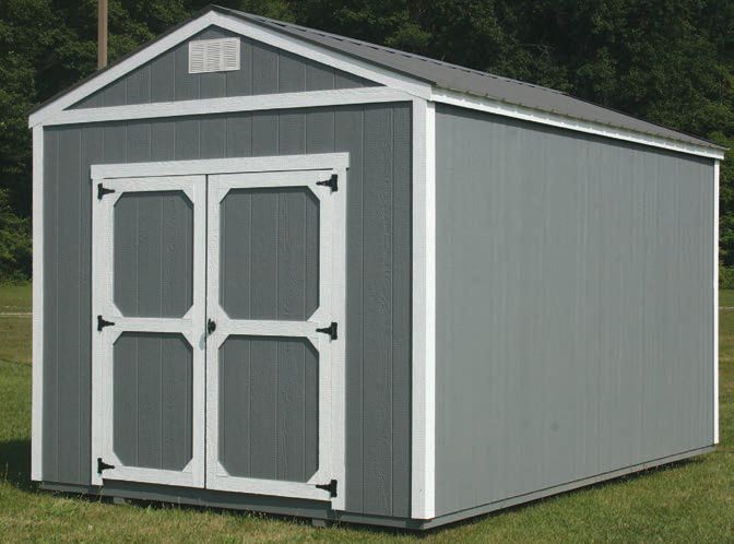 A gray and white shed is sitting in the middle of a grassy field.
