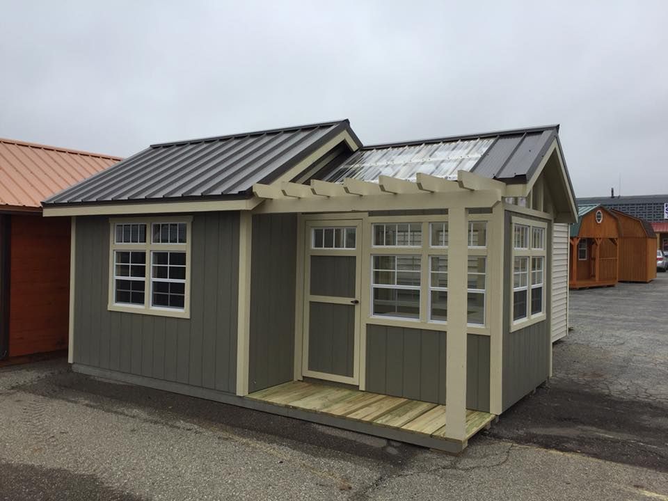 A small shed with a pergola on top of it