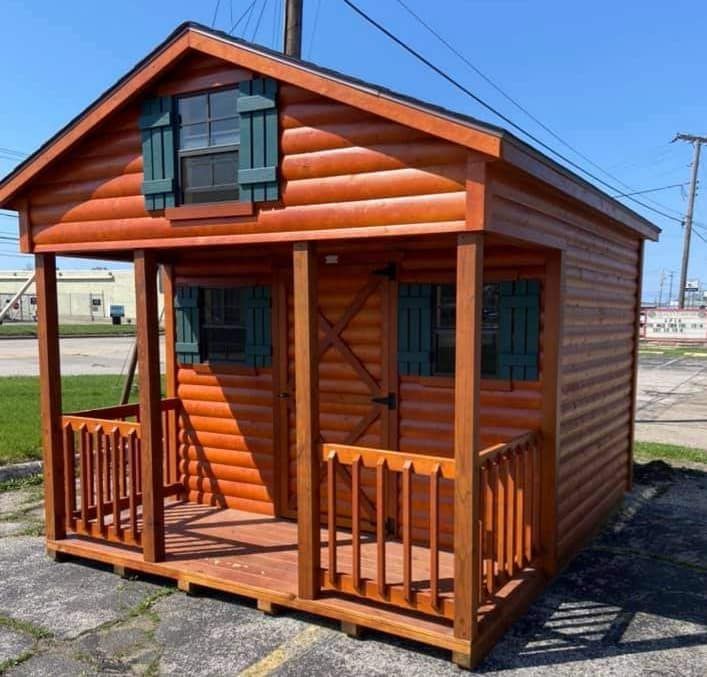 A small log cabin with a porch and green shutters