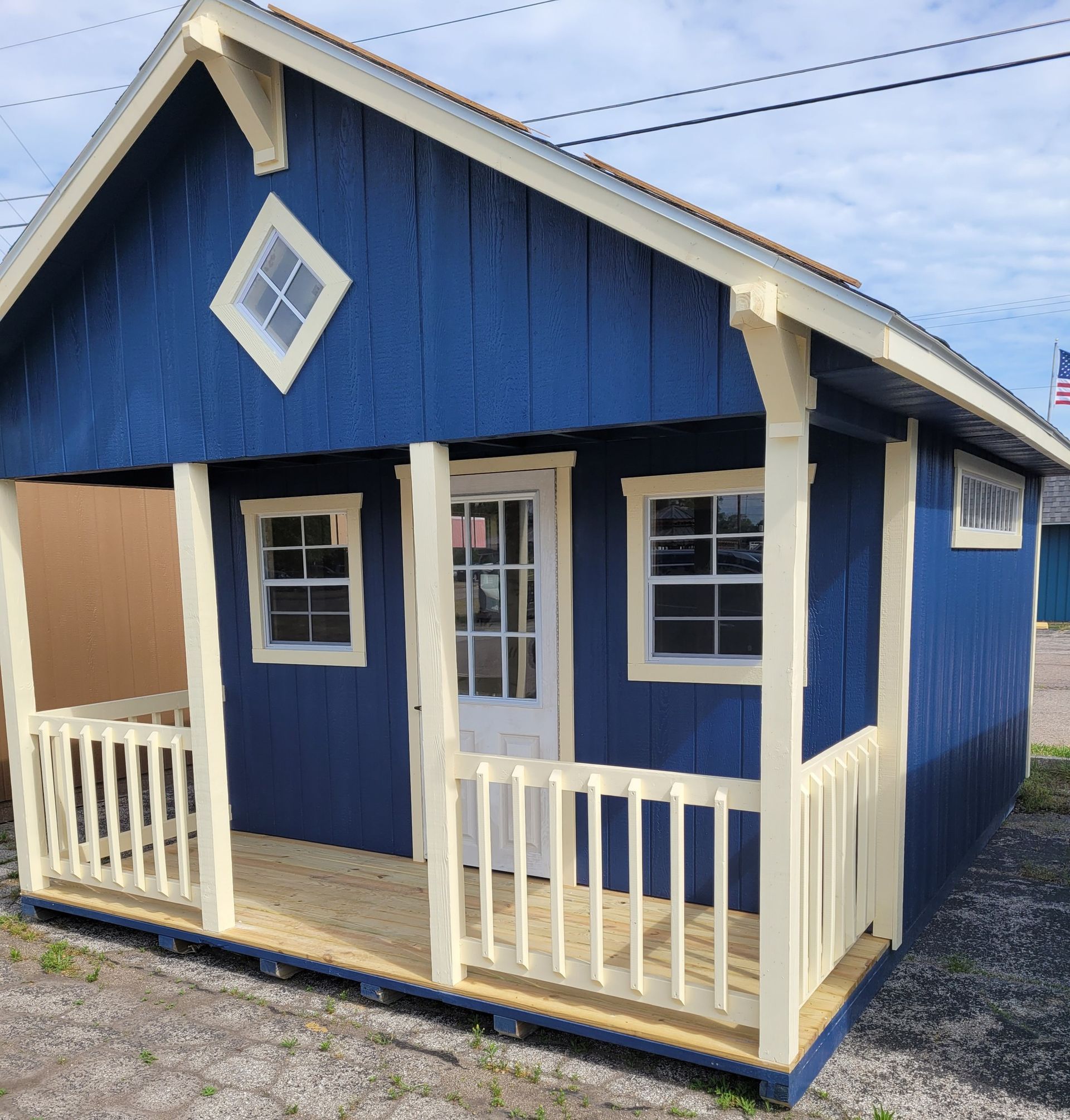 A small blue house with a porch and an american flag in the background