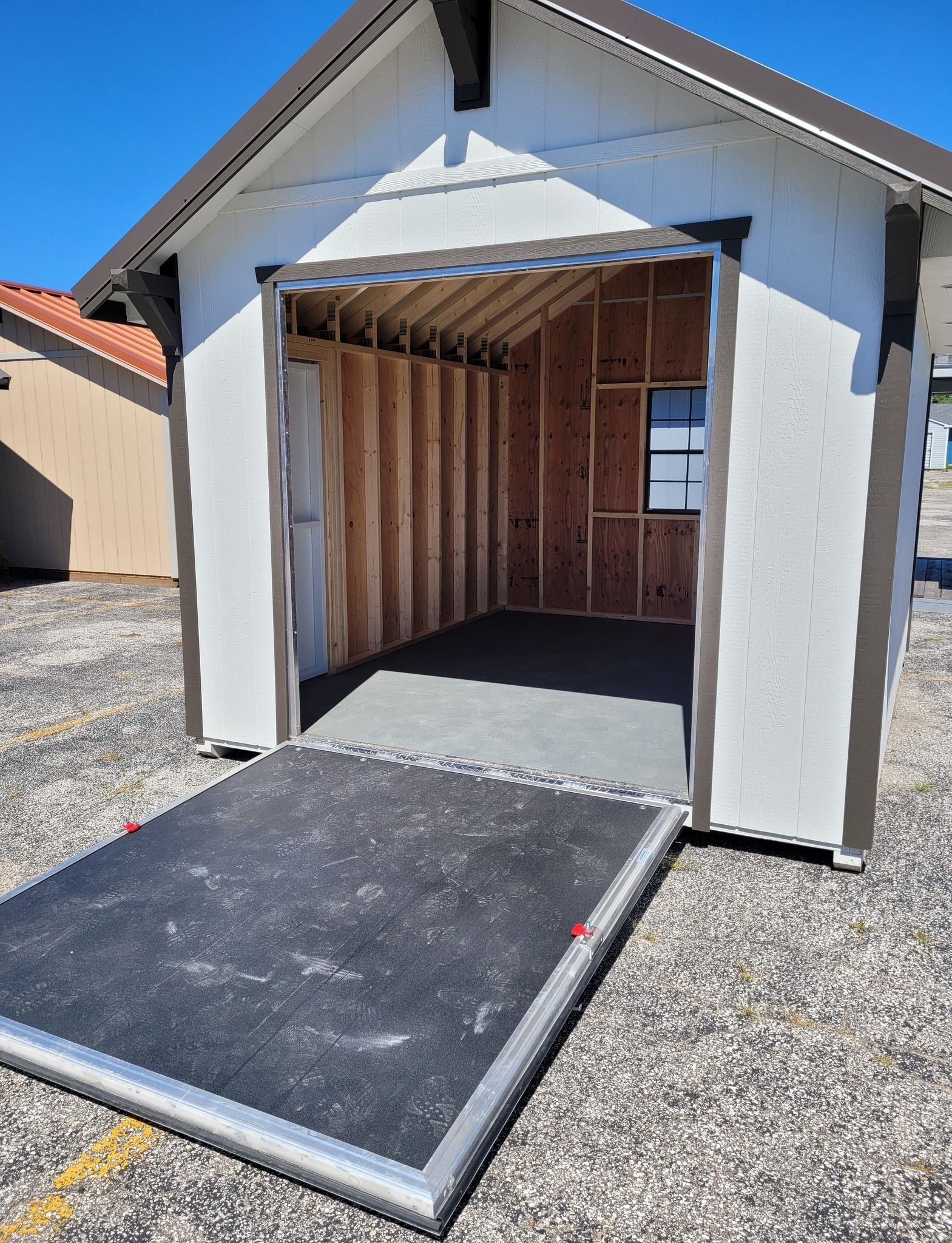 A small white shed with a ramp in front of it