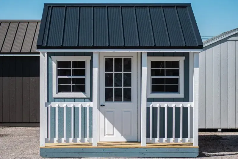 A small white house with a black roof and a porch.