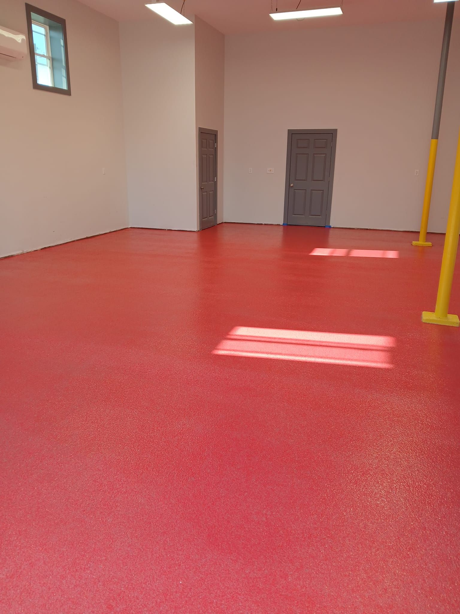 A large empty room with a red floor and white walls.