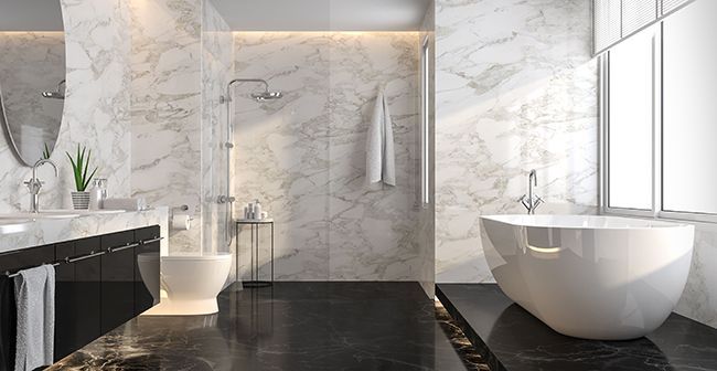 Modern luxury bathroom with marble walls, black floor, freestanding tub, vanity, and walk-in shower.