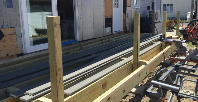 Wooden frame and posts on a construction site beside a building, with stacked metal rails and tools.