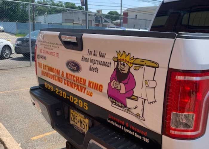 Pickup truck with a colorful plumbing and heating business sign on the side, parked outdoors.