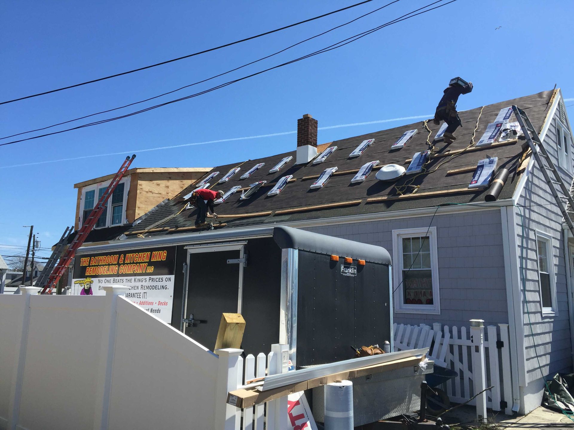 Damaged house roof with missing shingles and a construction sign, blue sky overhead