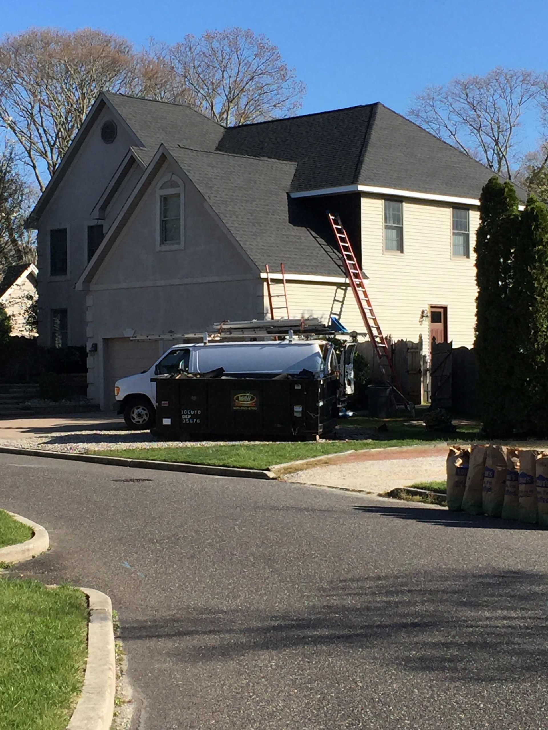 Suburban house with a black pickup truck in the driveway and an American flag by the front steps.