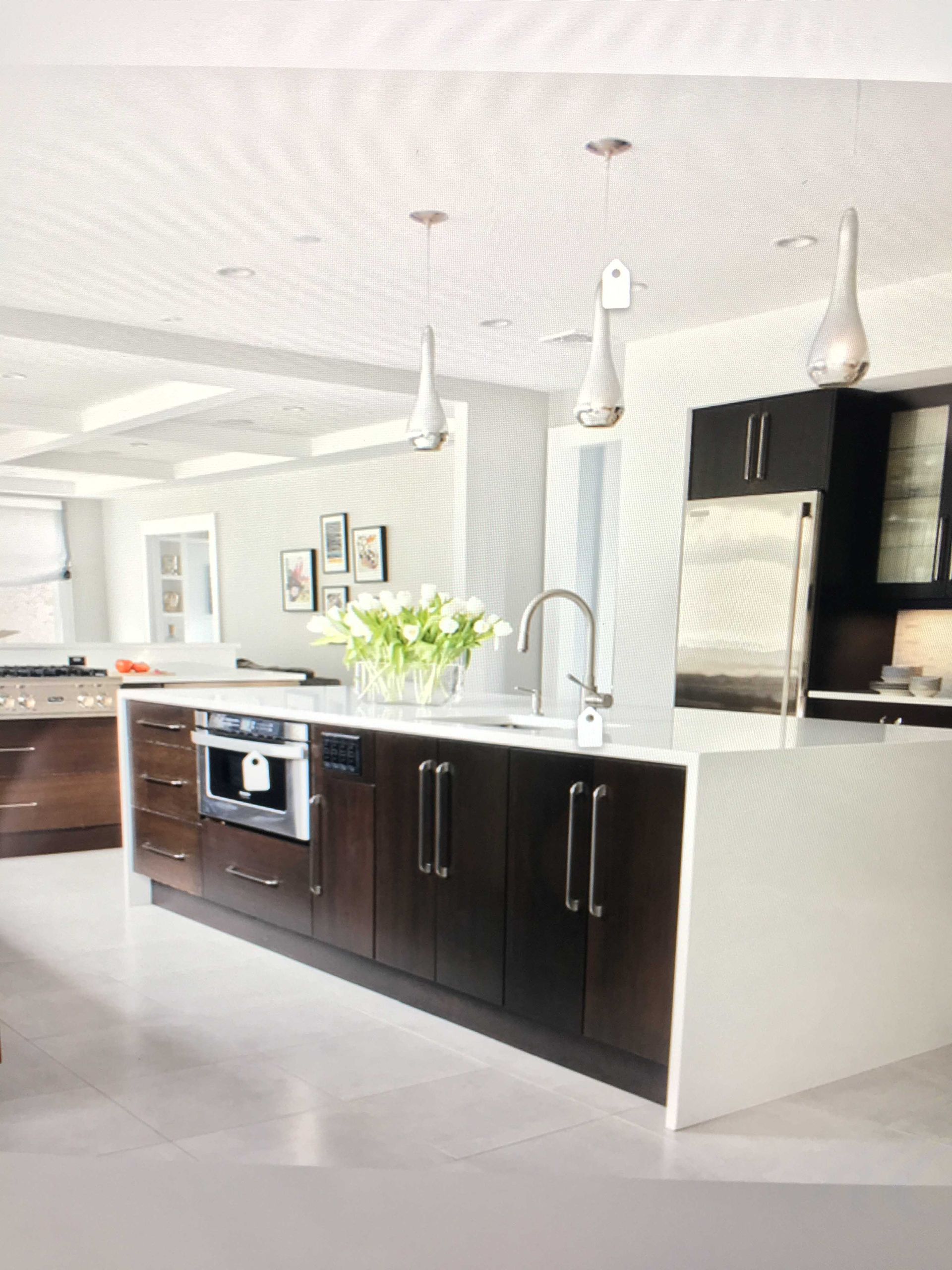 Modern kitchen with dark cabinets, white island, pendant lights, and stainless steel appliances