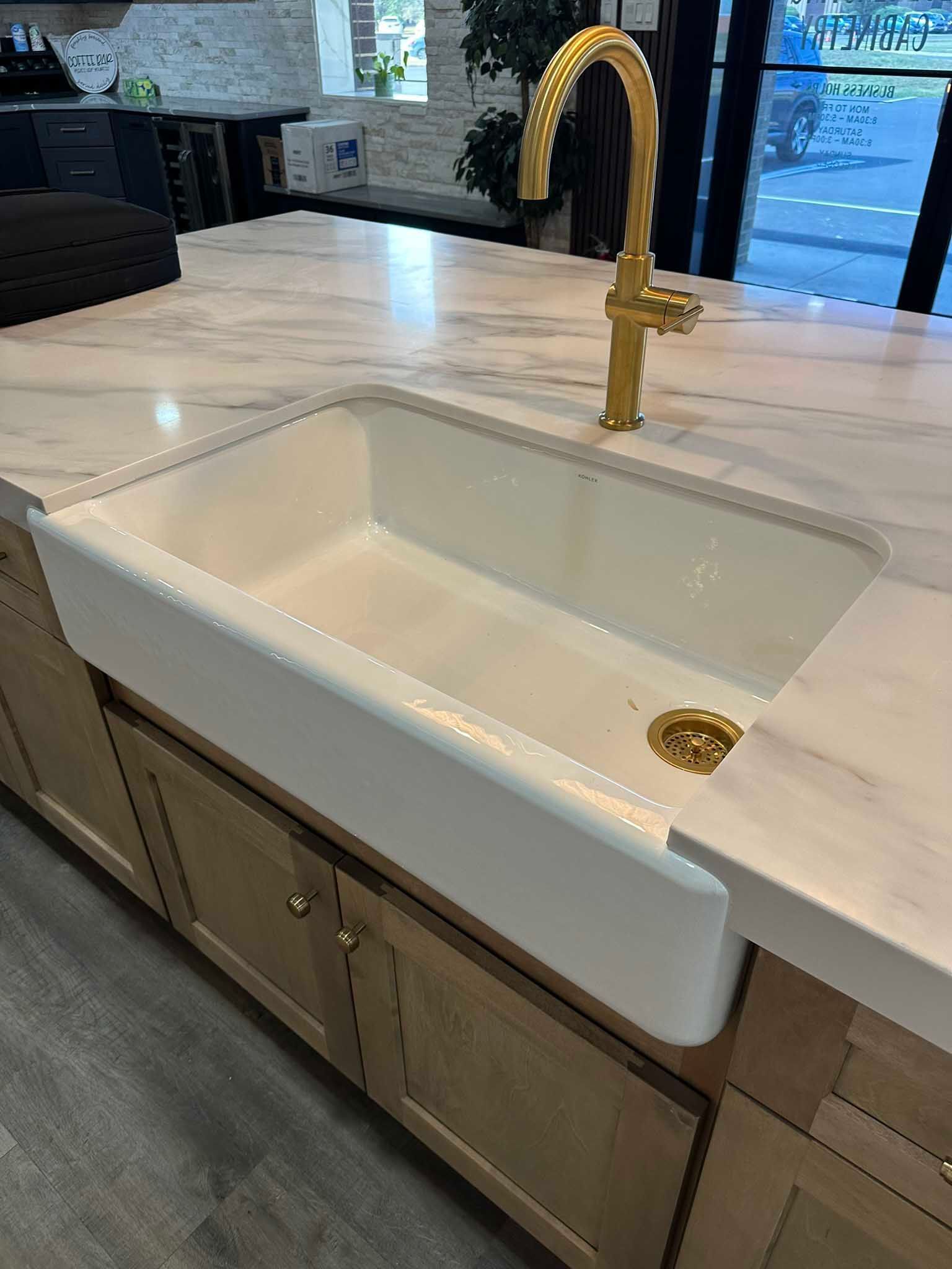 Kitchen sink with white countertop and brass faucet in a modern kitchen