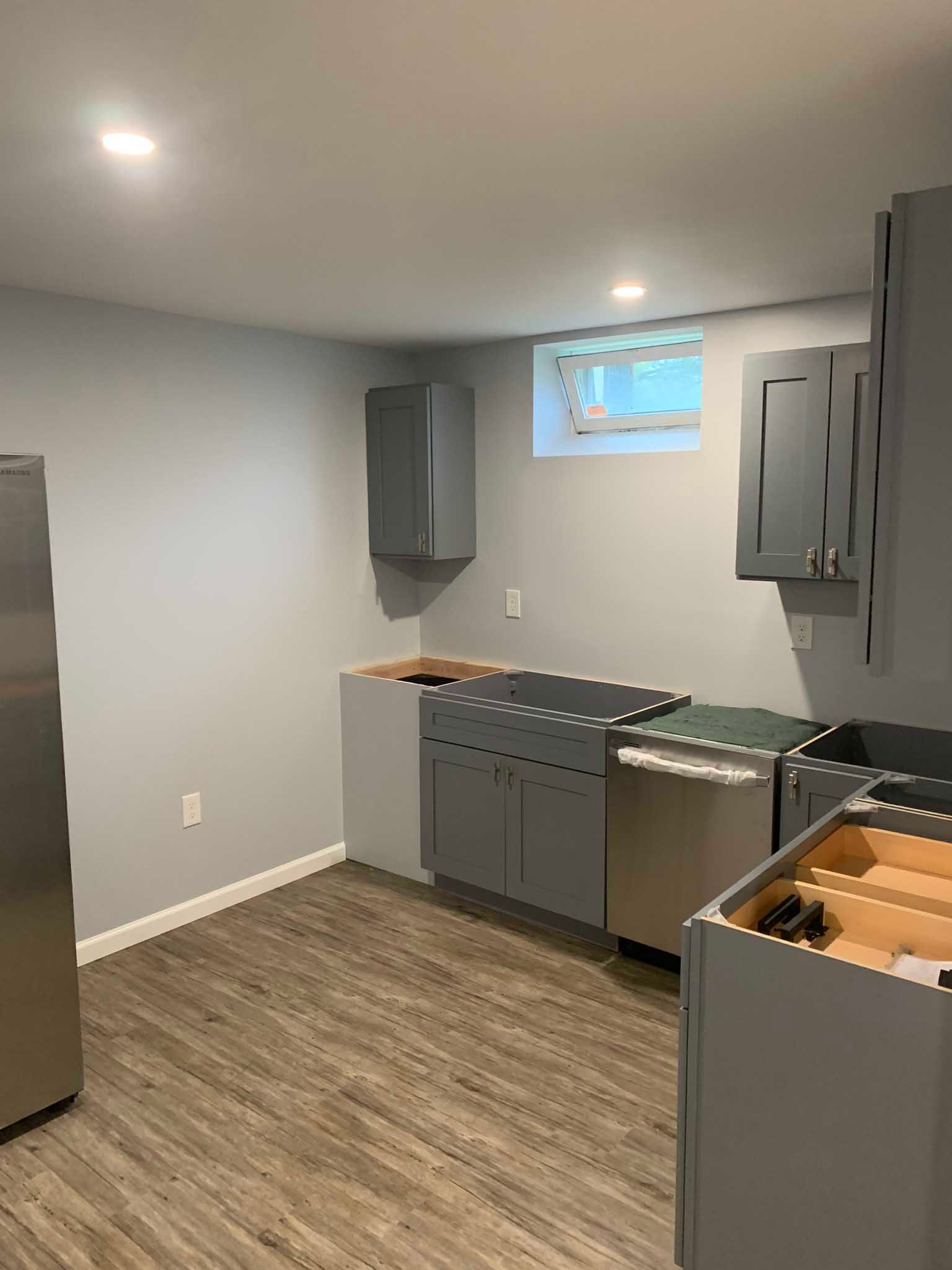 Small kitchen with gray cabinets, stainless steel appliances, and a window near the ceiling.