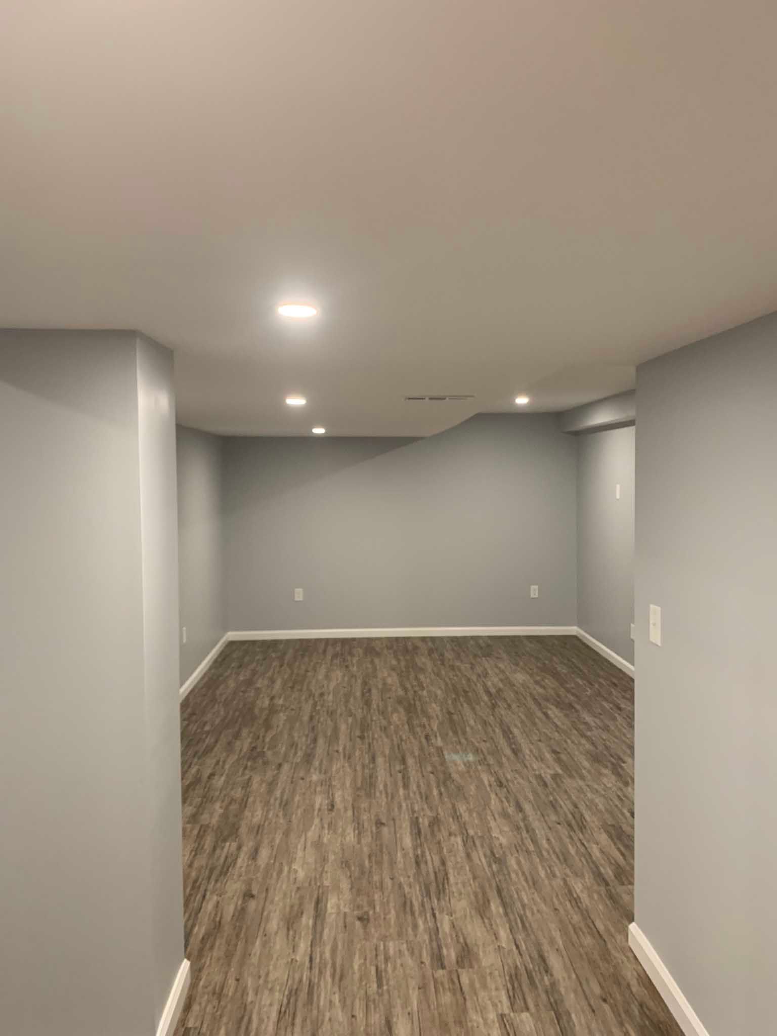 Empty gray basement room with carpet, recessed lights, and a low ceiling