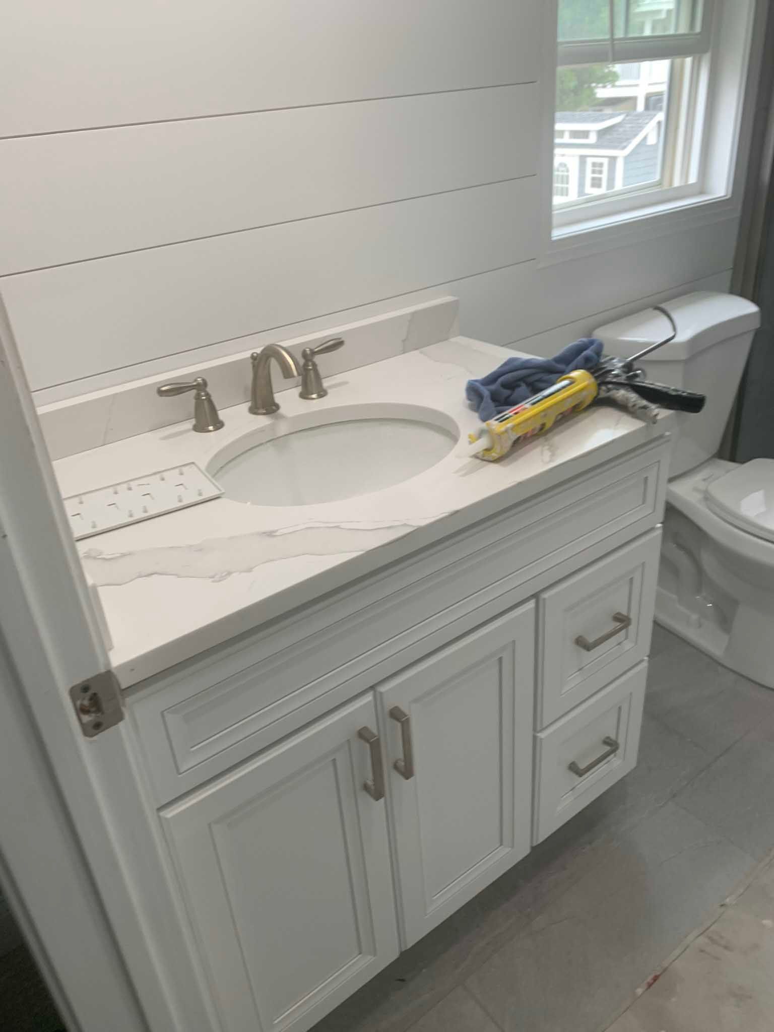 White bathroom vanity with sink, mirror, and a hair dryer on the counter