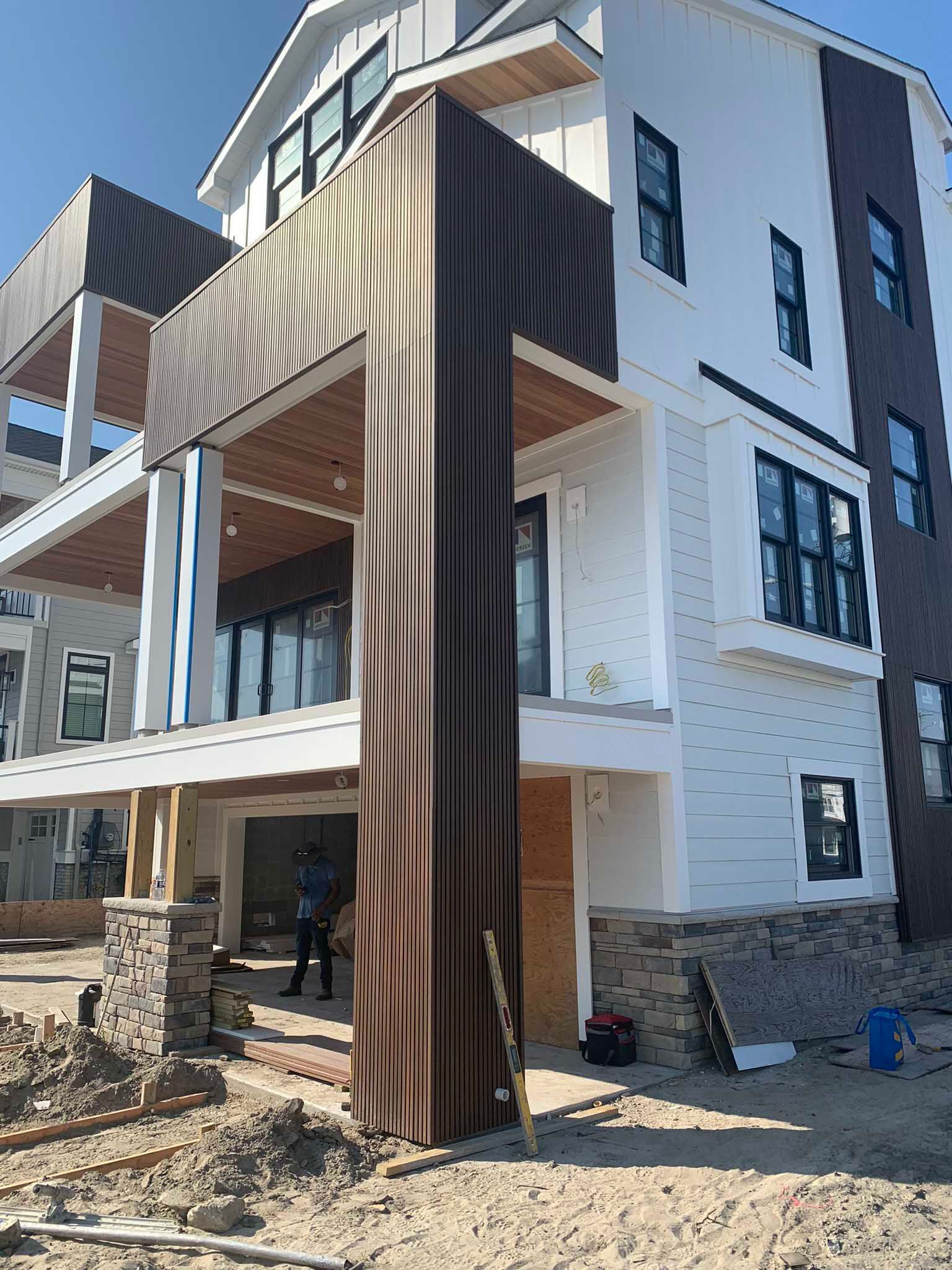 Modern two-story house with black-and-white exterior and a covered balcony supported by wood slats