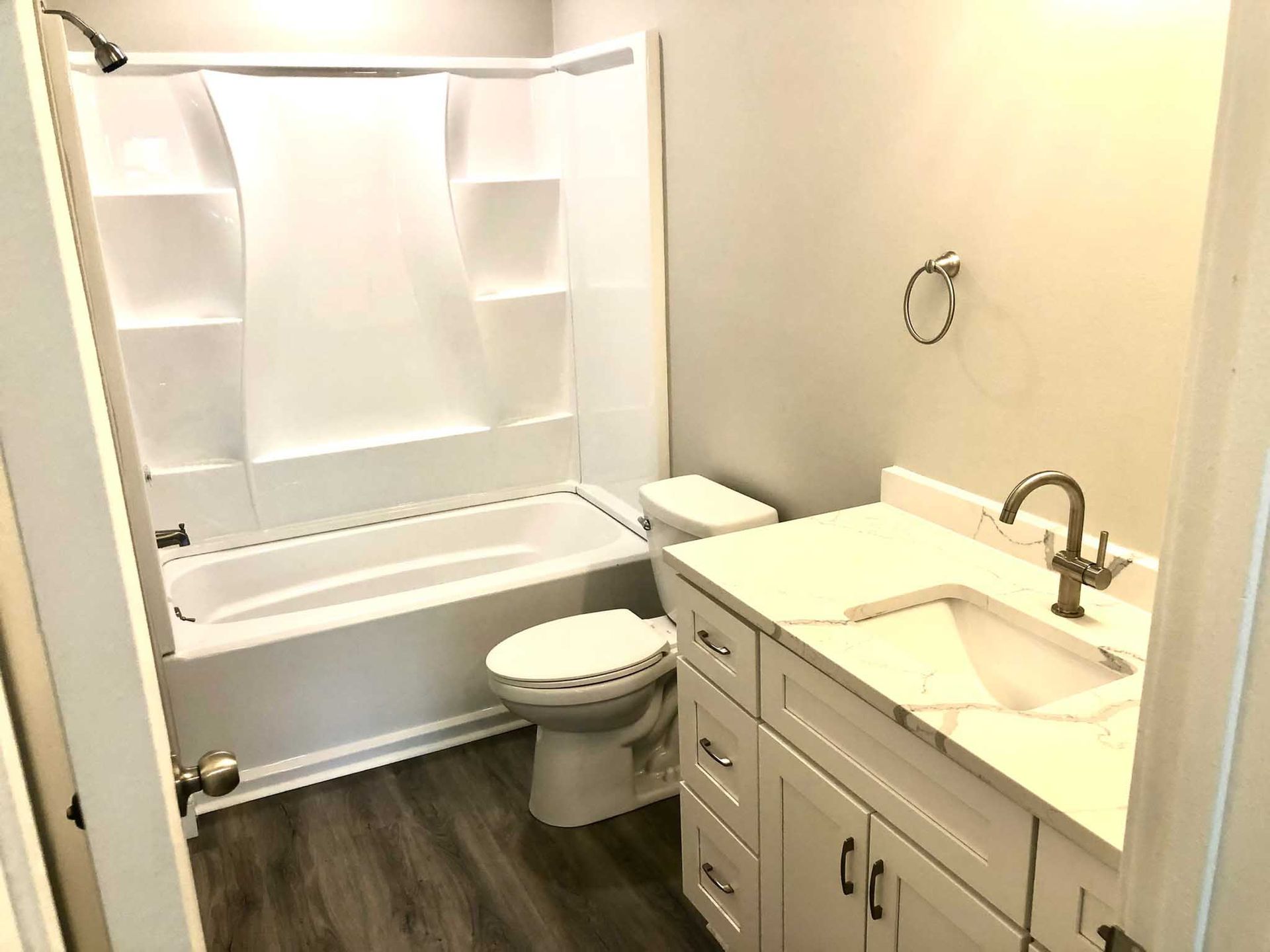 Accessible bathroom with bathtub shower, toilet, and vanity sink in a small tiled room