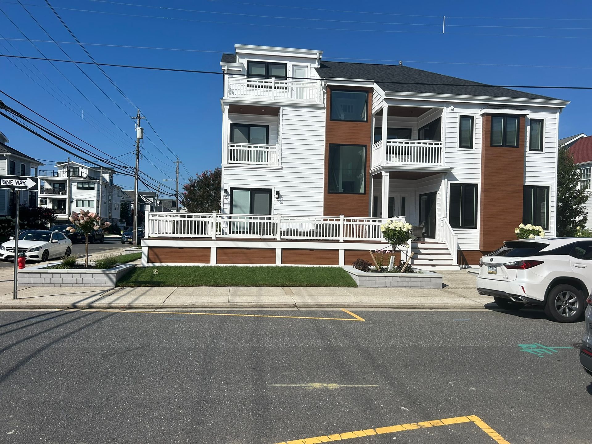View of a two-story white house showing the sidewalk and some grass outside the house.