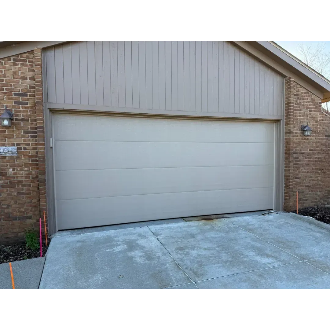 Closed white garage door on a brick house with a concrete driveway
