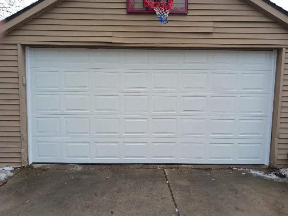 Closed white garage door on a beige house exterior with a basketball hoop above it