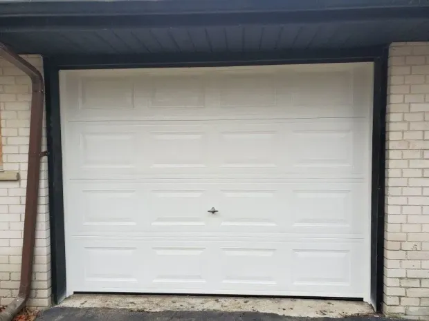 Closed white garage door in a brick exterior wall