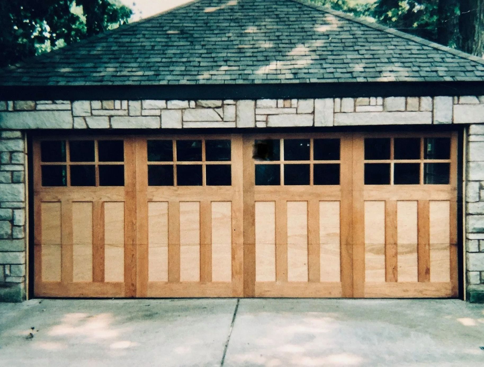 Wooden garage door with six panels on a stone house, front view