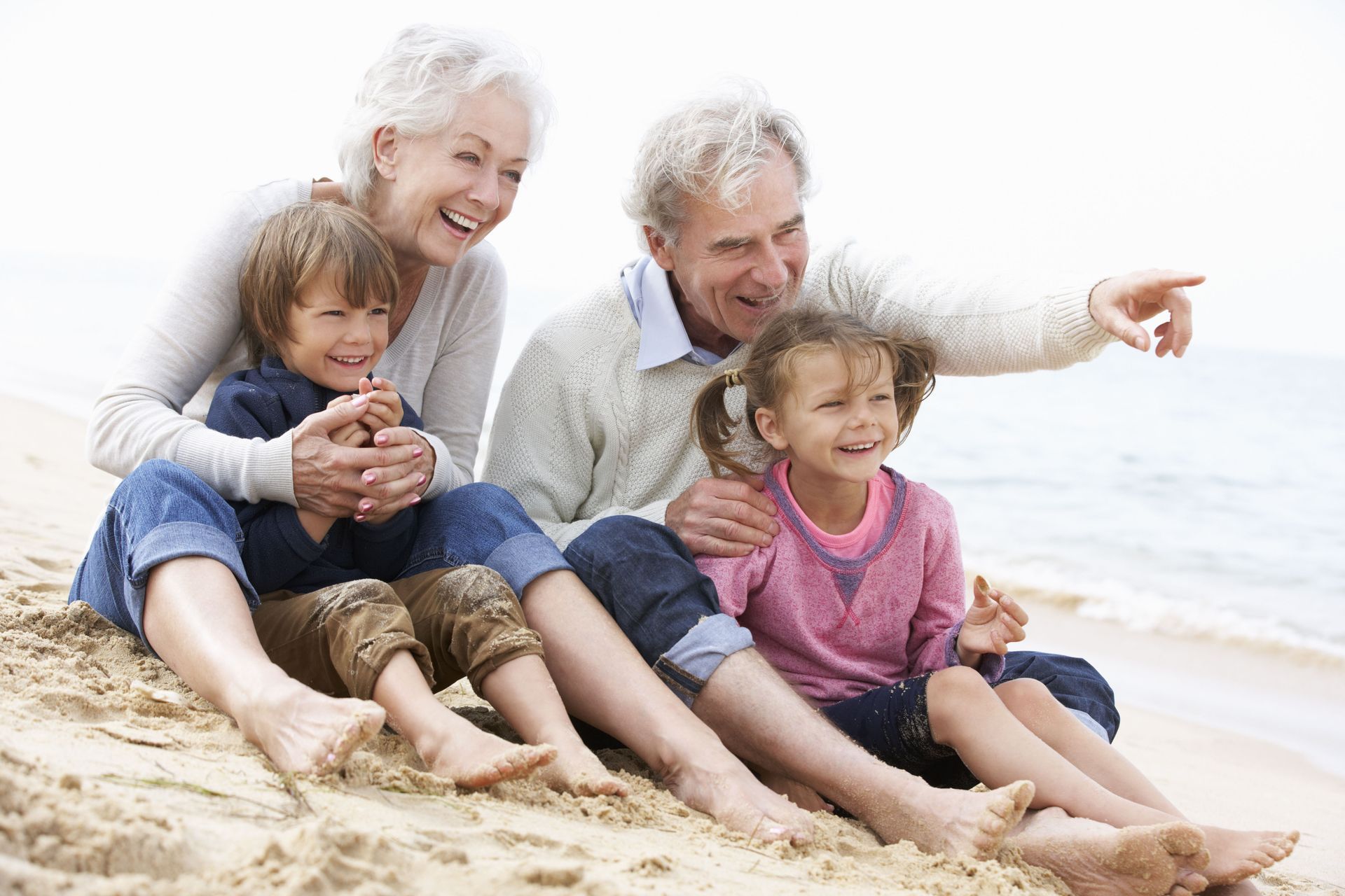 A family is sitting on the beach looking at the ocean.