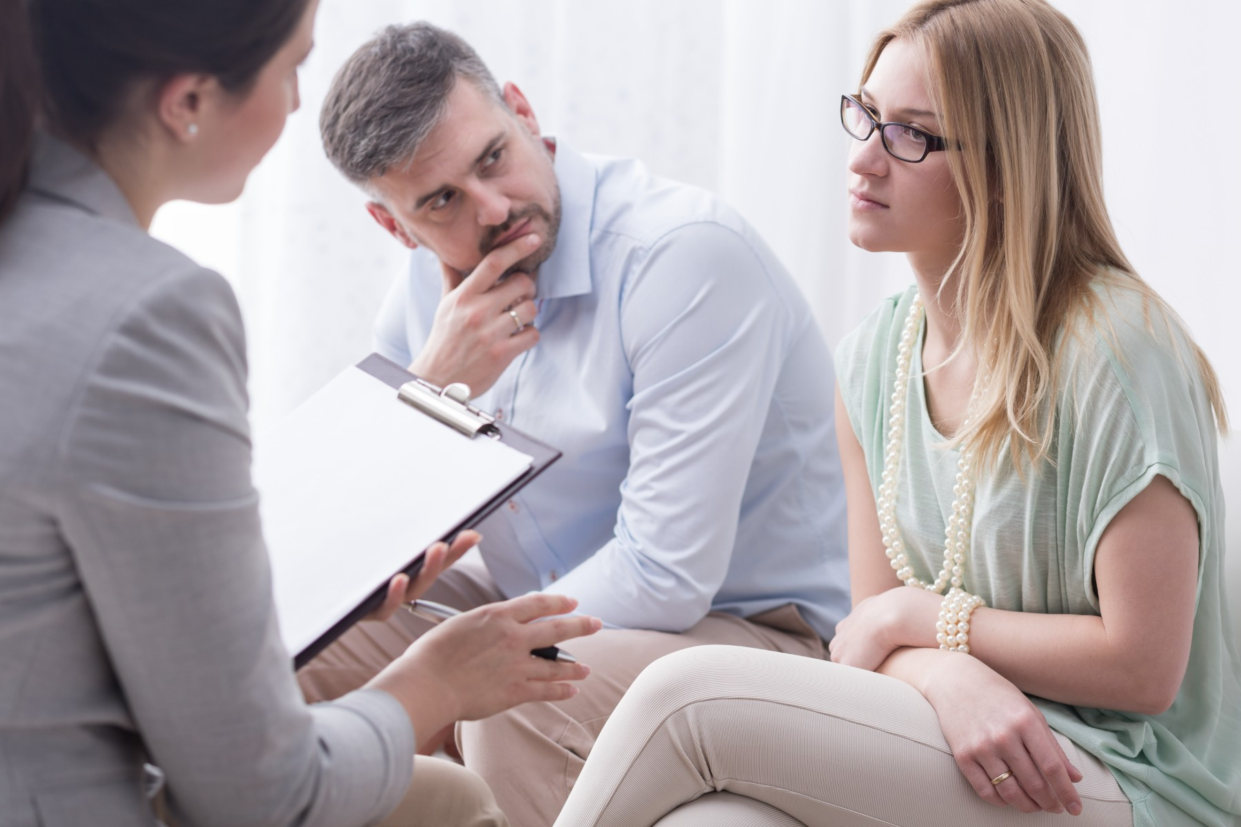 A man and a woman are sitting on a couch talking to a woman.