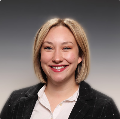 A woman wearing a black jacket and white shirt smiles for the camera