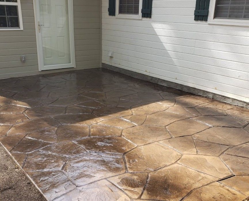 A patio with a stamped concrete design in front of a house.