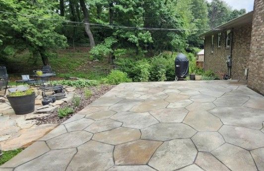A patio with a grill and chairs in front of a house.