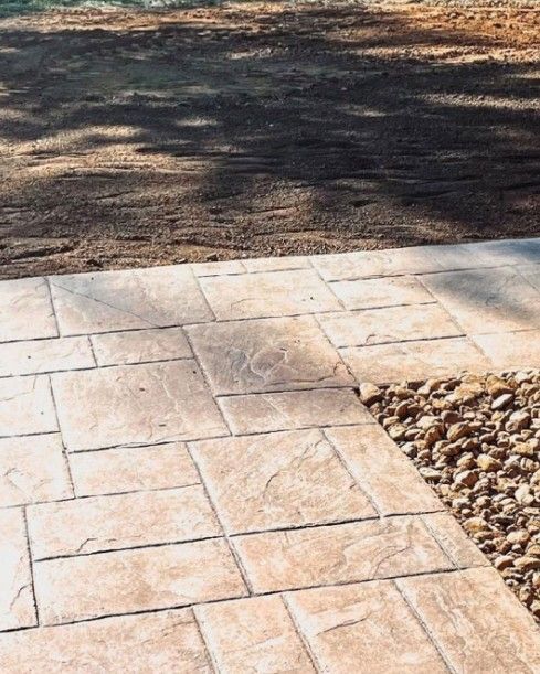A brick walkway leading to a dirt road with trees in the background