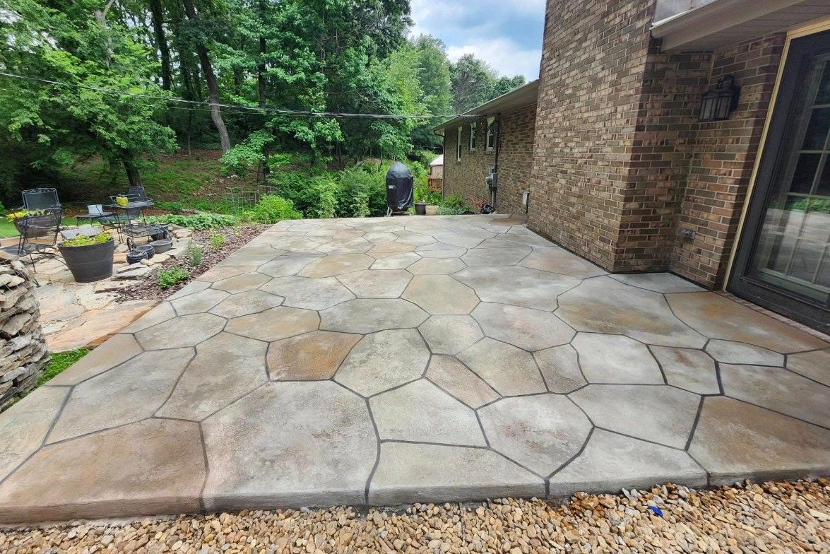 A large stone patio in front of a brick house.