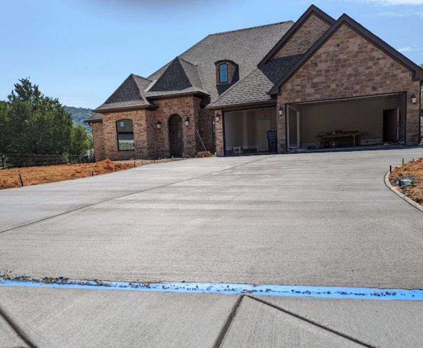 A large brick house with a concrete driveway in front of it.