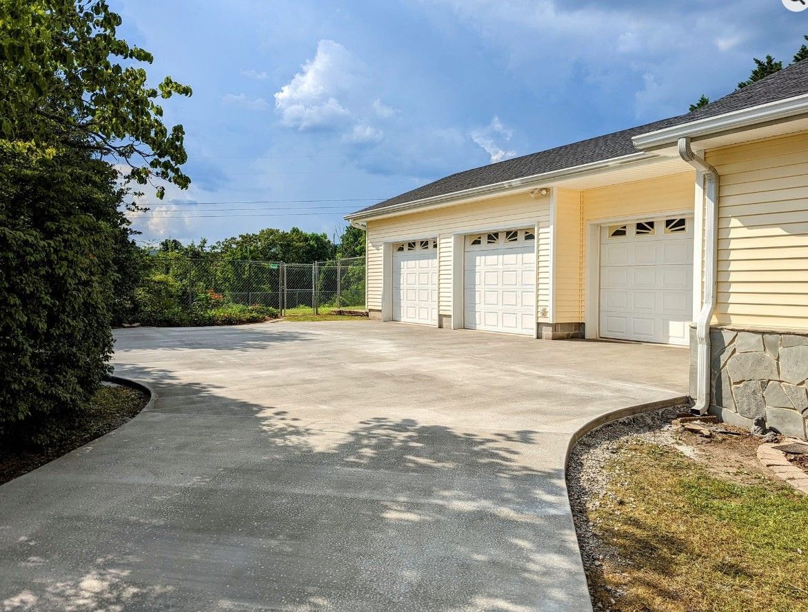 A house with three garage doors and a driveway leading to it.