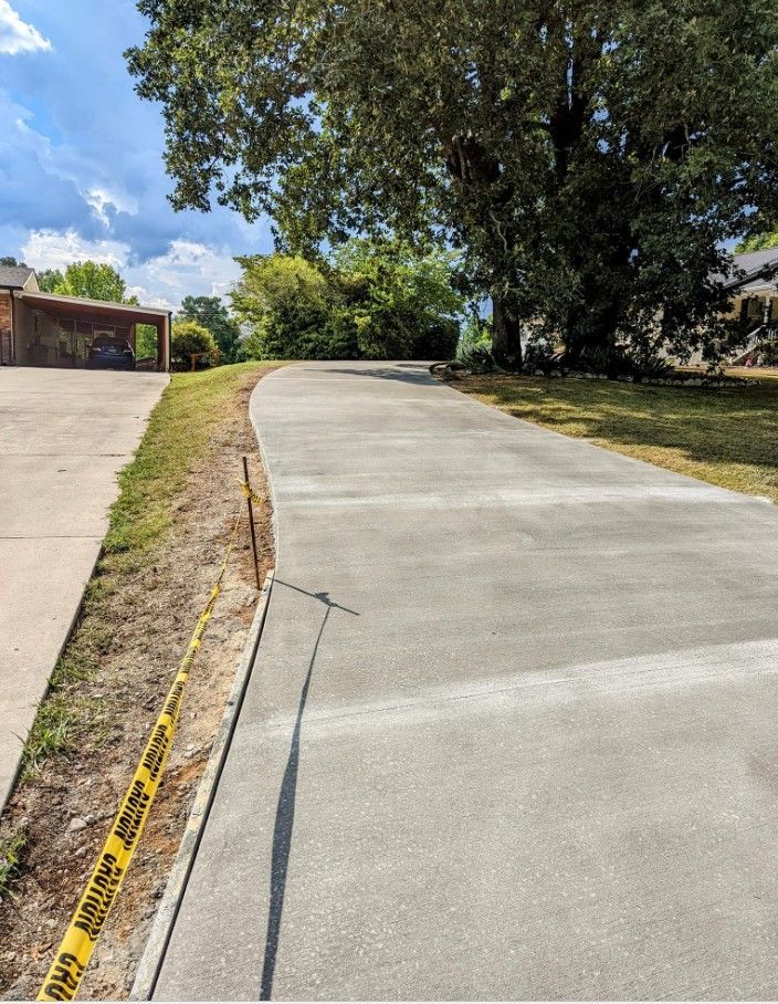 A concrete driveway with a yellow caution tape on the side