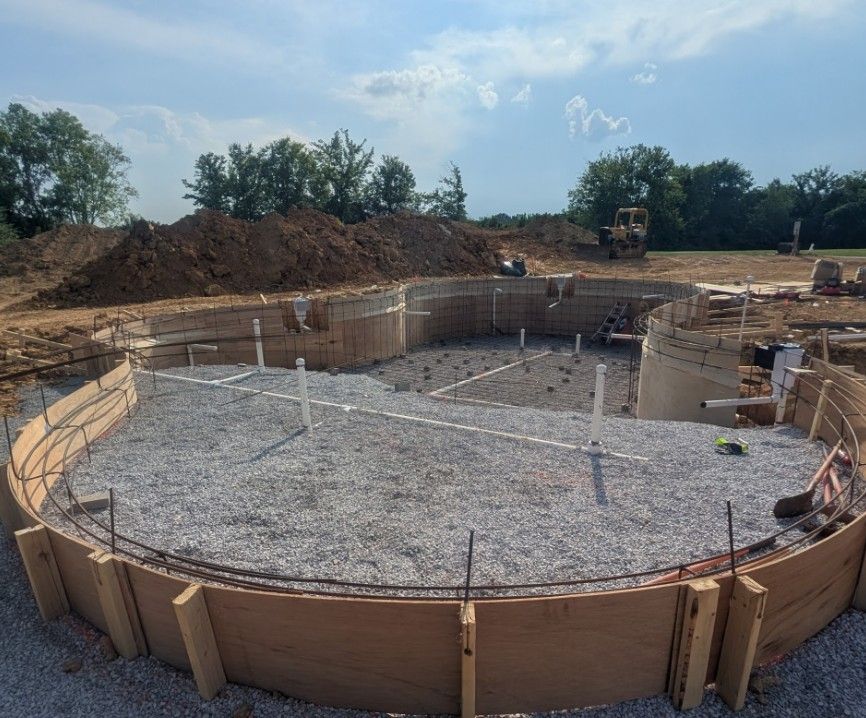 A large circular swimming pool is being built in a dirt field.