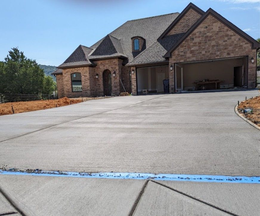 A large brick house with a concrete driveway in front of it