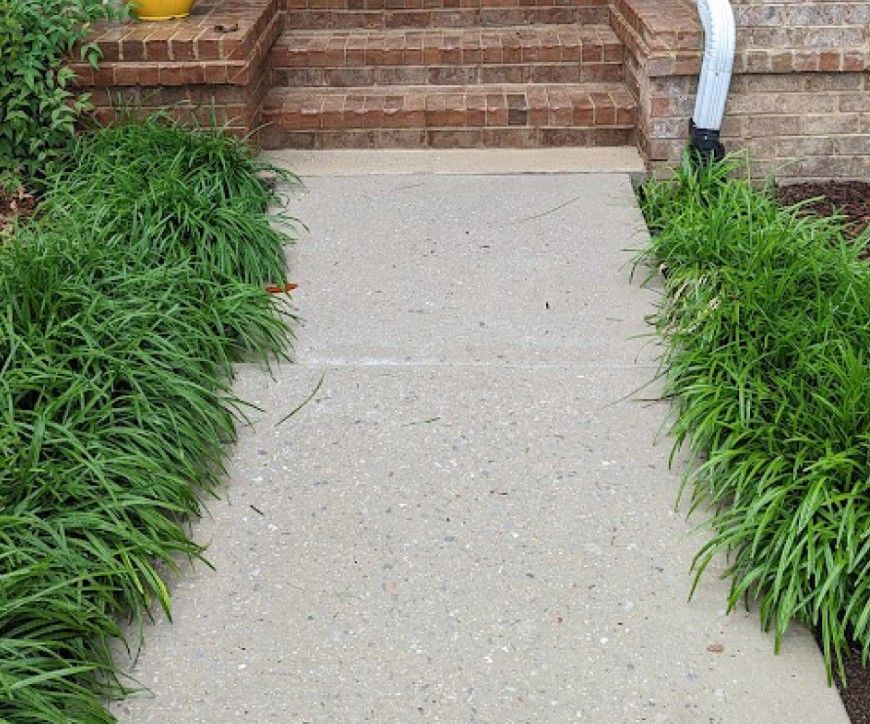 A concrete walkway leading to a brick house