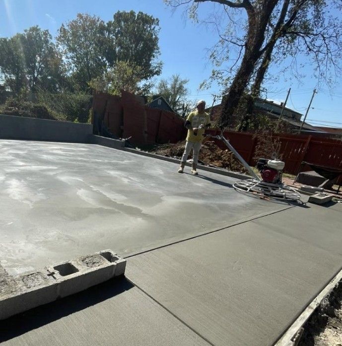 A man is spreading concrete on a sidewalk