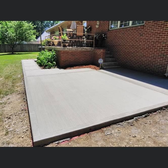 A brick house with a concrete patio in front of it.
