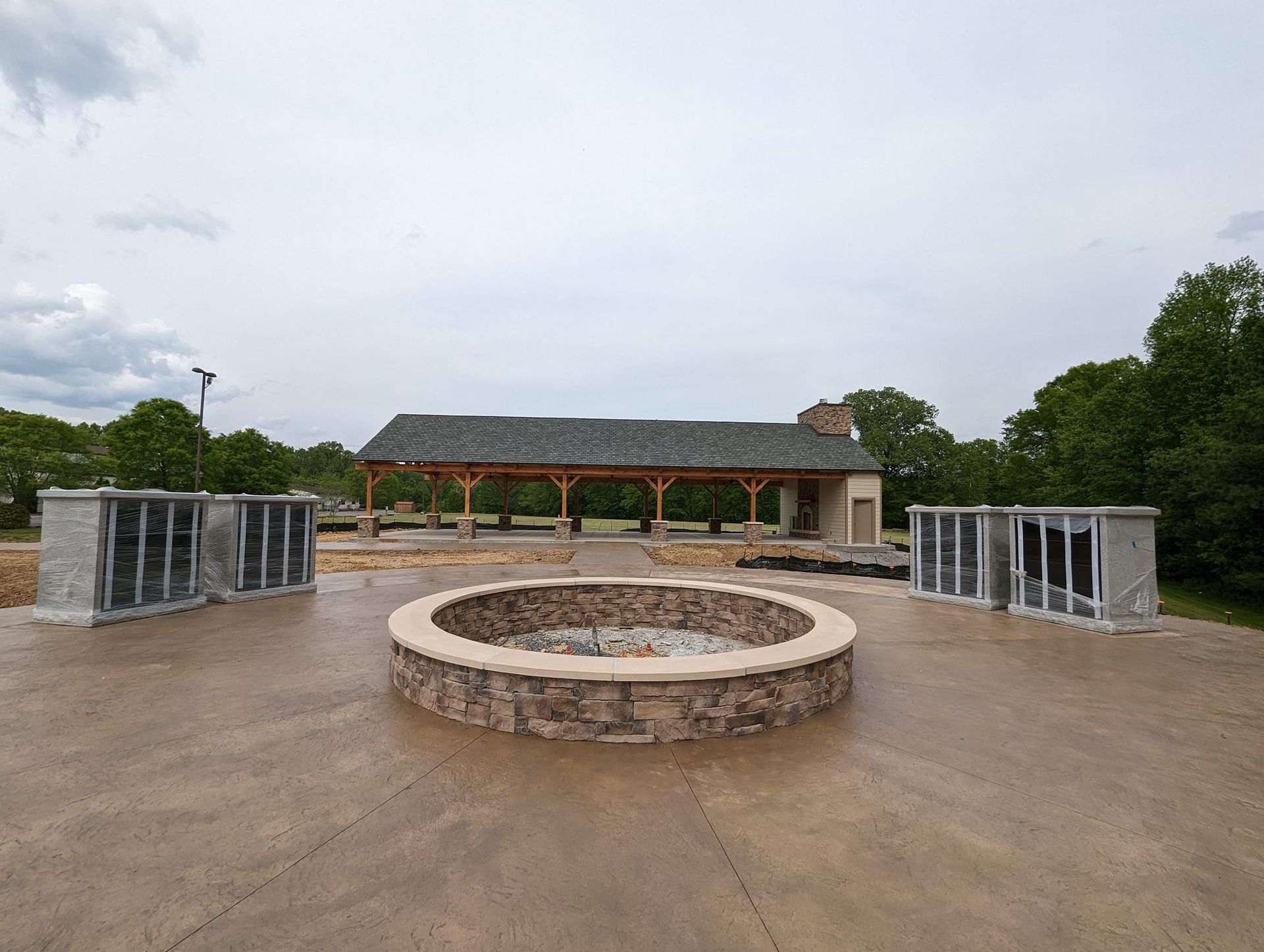 A fire pit is in the middle of a concrete patio in front of a building.
