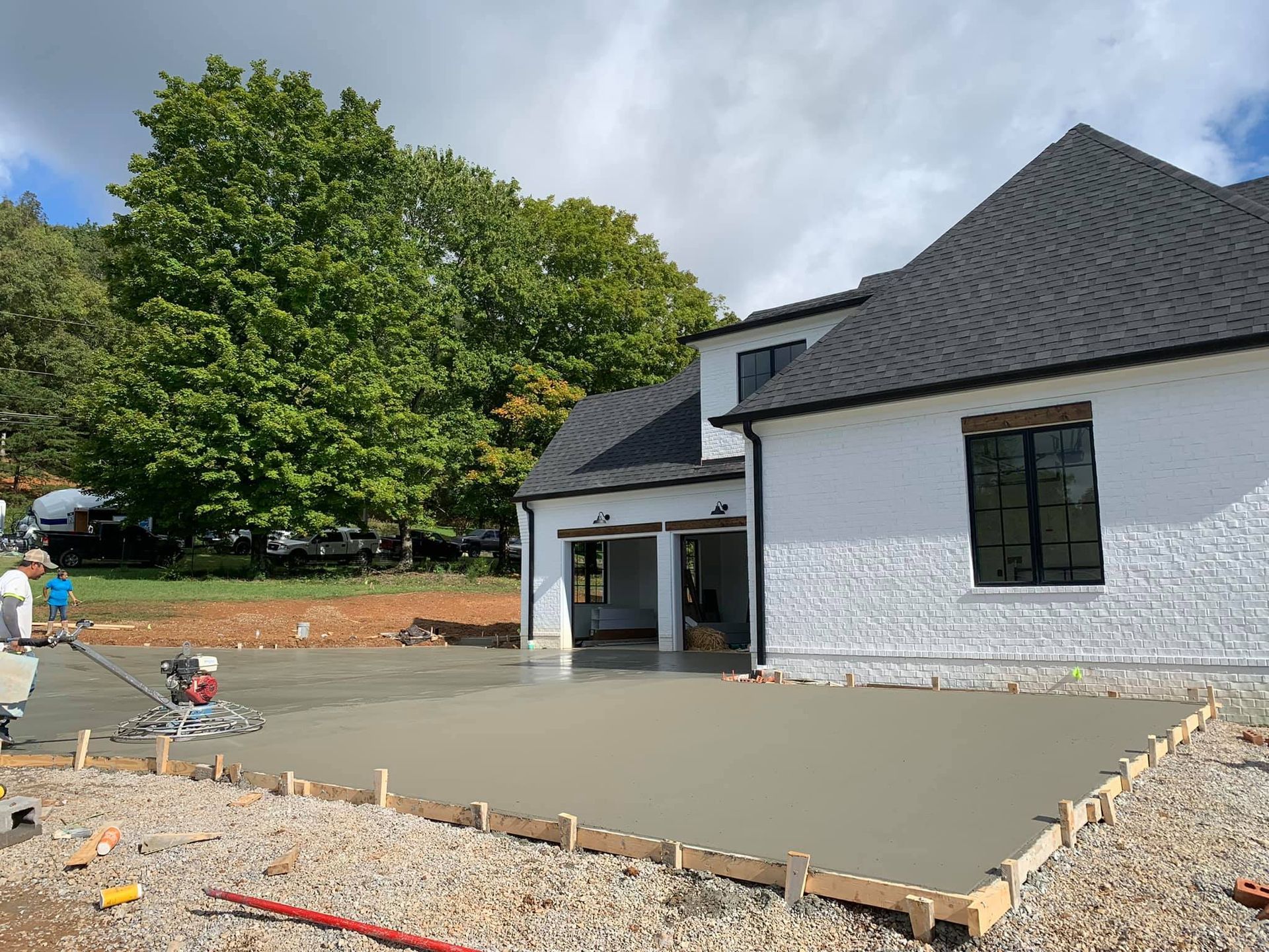 A white house with a black roof is being built.