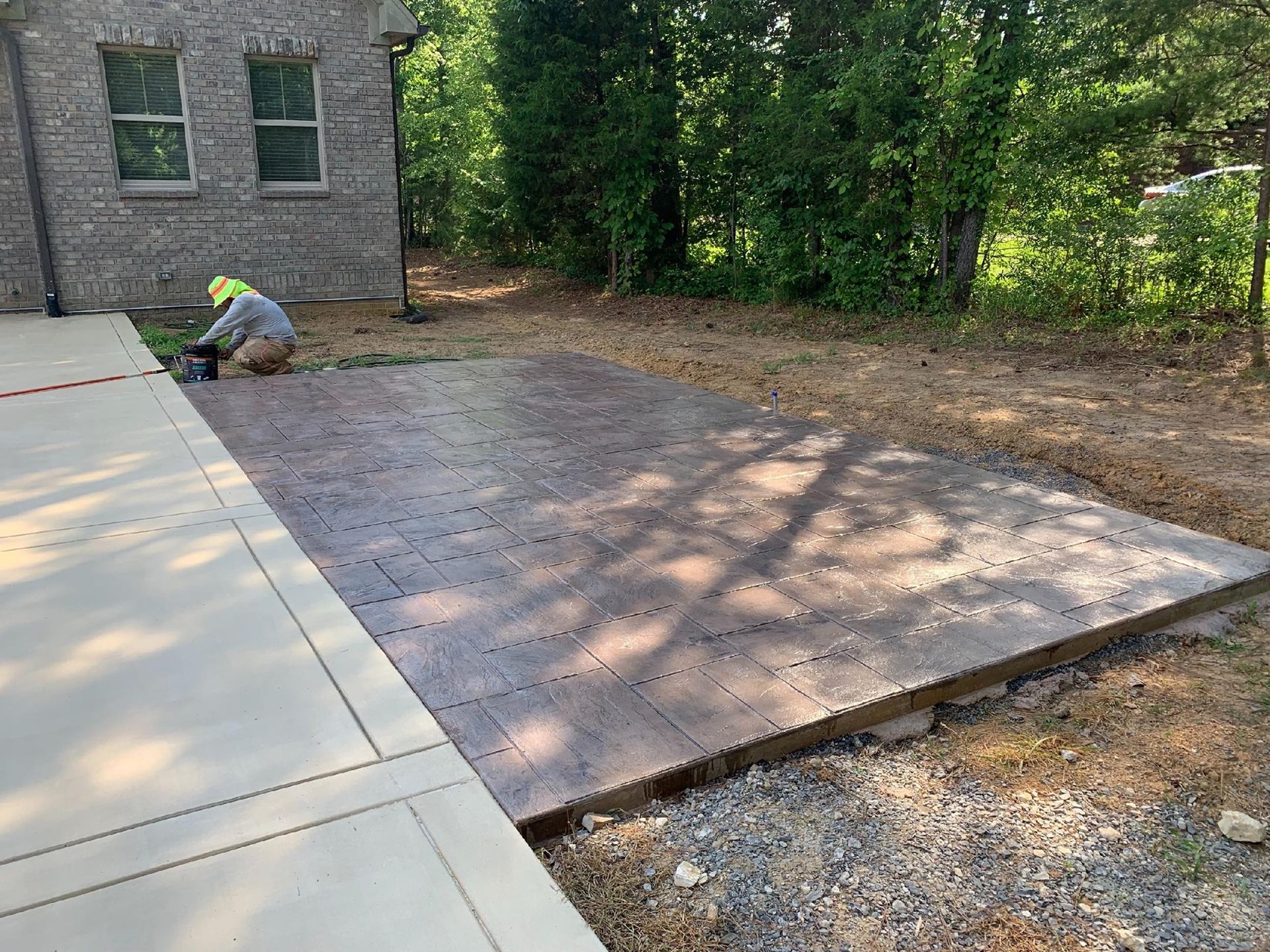 A man is working on a concrete driveway in front of a house.