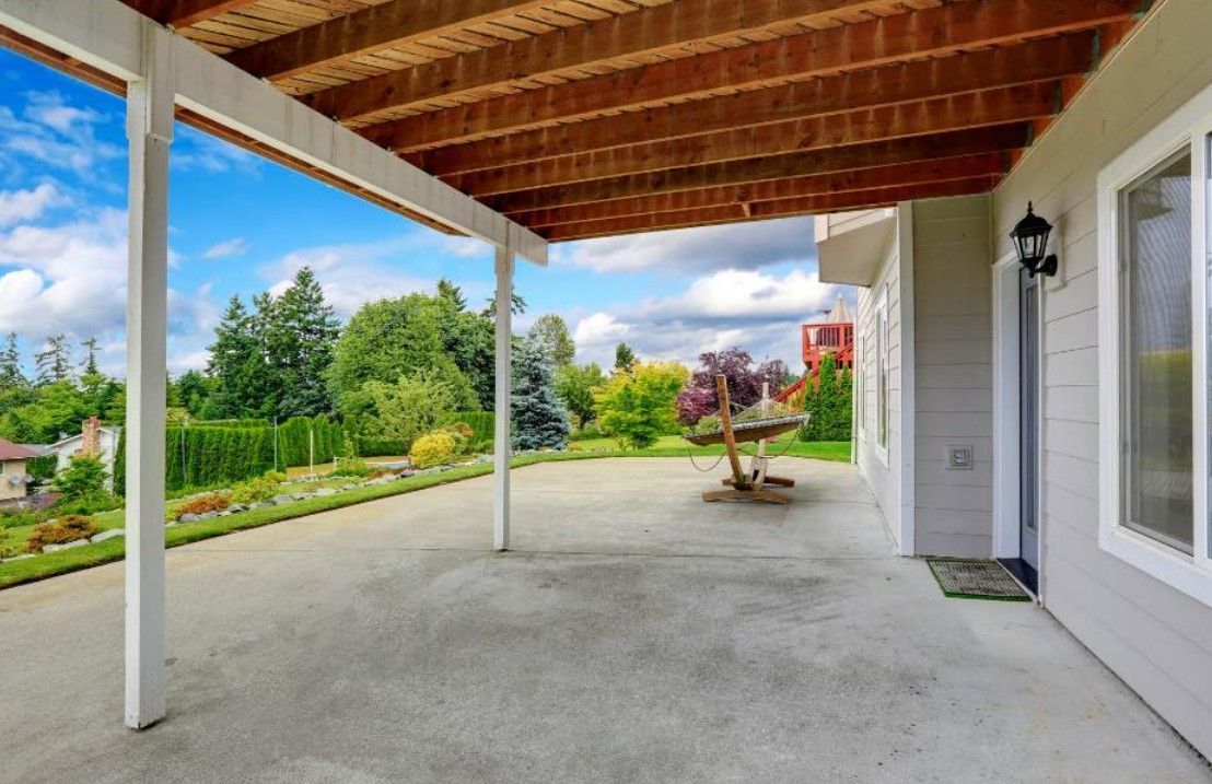 A covered patio with a wooden ceiling and a table underneath it.